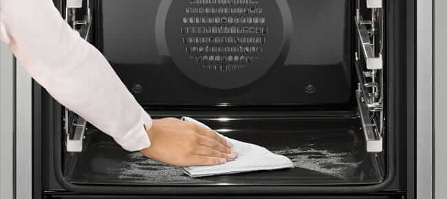 Backofen wird mit Tuch ausgewischt