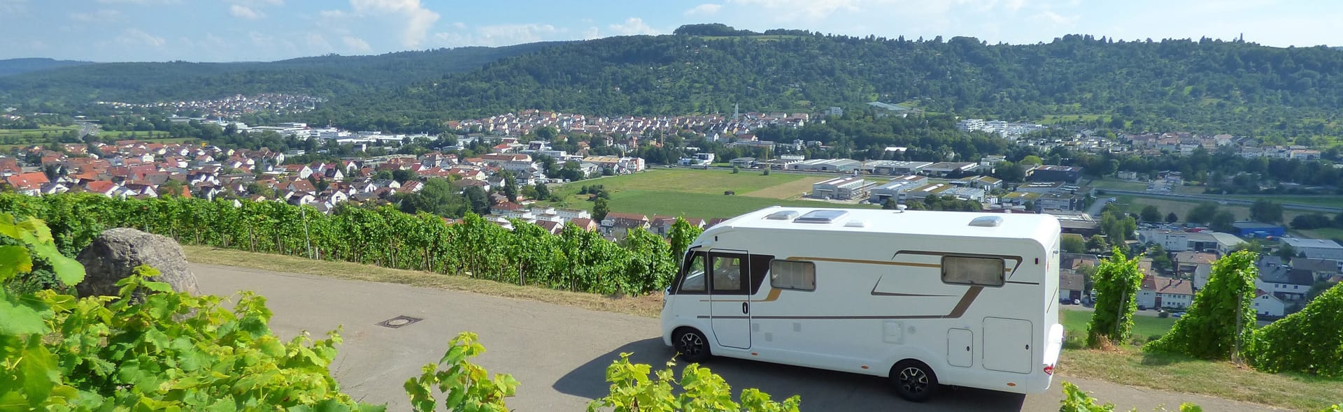 Wohnwagen auf Straße mit einer schönen Kleinstadt im Hintergrund