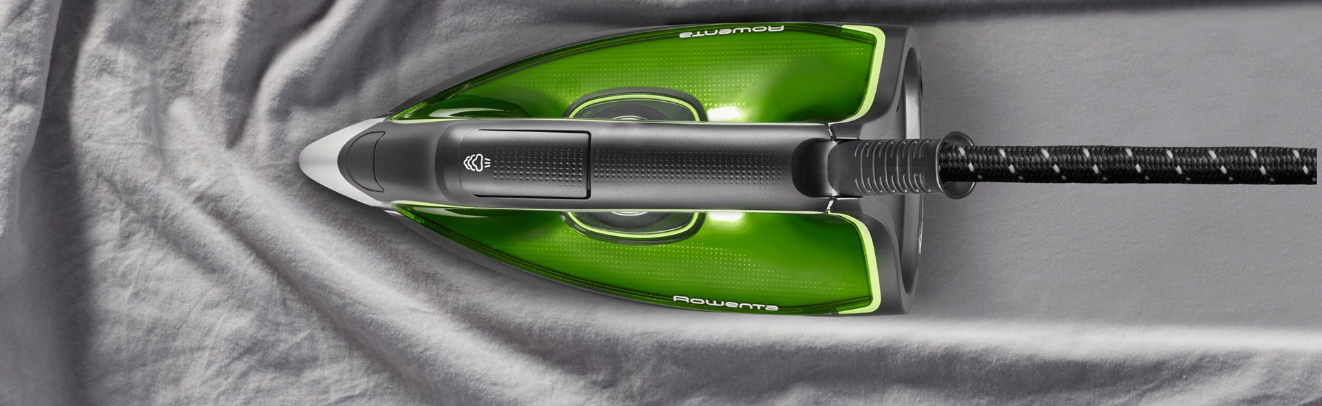 grünes Bügeleisen auf grauem Stoff