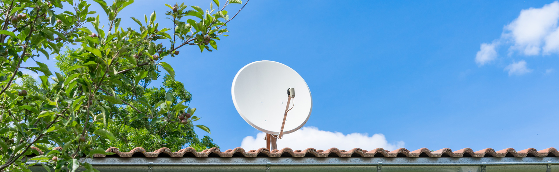 Satellitenschüssel auf Dach mit Wolken im Hintergrund
