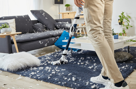 Person staubsaugt den Boden in chaotischem Zimmer