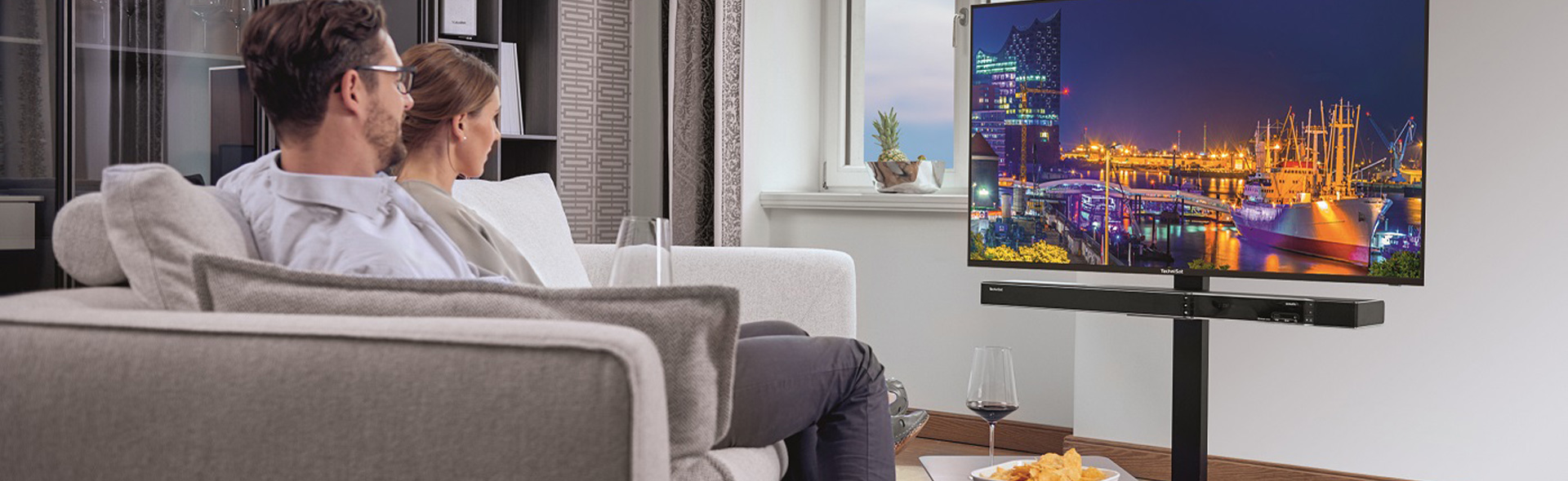 Mann und Frau auf Sofa vor Fenseher