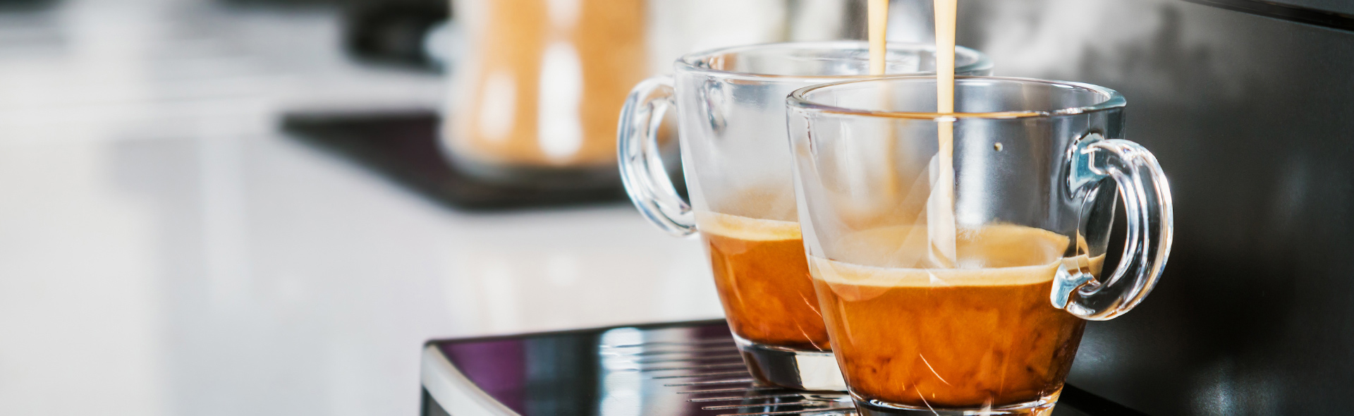 Zwei Kaffeetassen werden gleichzeitig in Kaffeemaschine befüllt