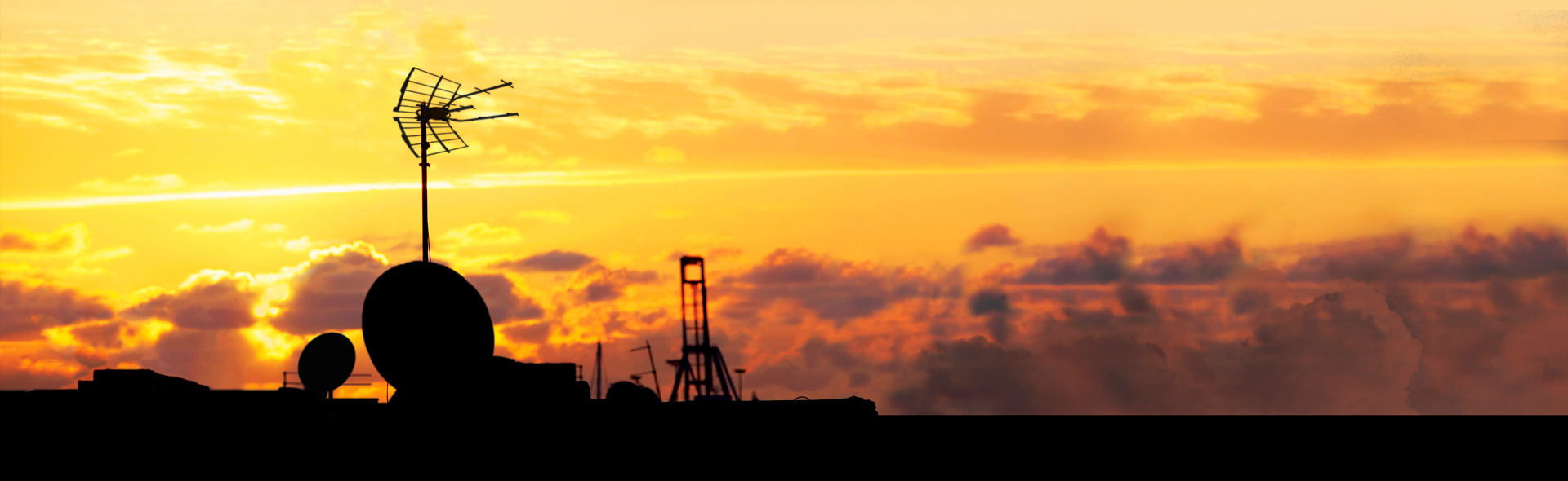 mehrere Umrisse von Antennen vor einem Sonnenuntergang