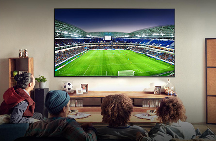 Vier Leute schauen Fußball auf einem Fernseher an der Wand