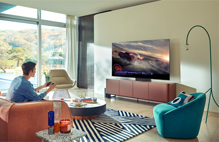 Mann spielt mit einem Controller ein Rennspiel an einem Fernseher