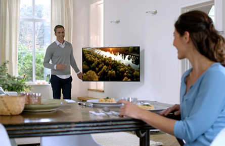 Mann und Frau in einem Wohnzimmer neben laufendem Fernseher