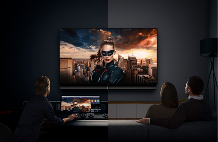 Drei Leute sitzen vor einem Fernseher und schauen einen Film welcher auch auf einem Laptop angezeigt wird