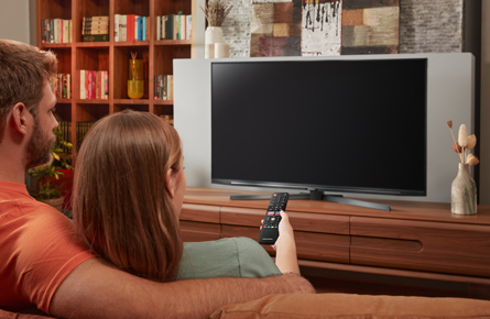 Paar sitzt auf einem Sofa vor Fernseher