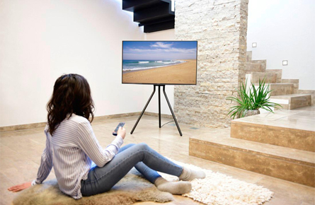 Frau sitzt vor einem Fernseher mit Standfuß