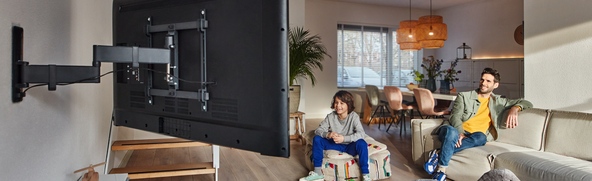 Vater und Sohn schauen Fernseher welcher mit einer Wandhalterung befestigt ist