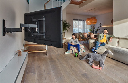 Vater und Sohn schauen Fernseher welcher mit einer Wandhalterung befestigt ist