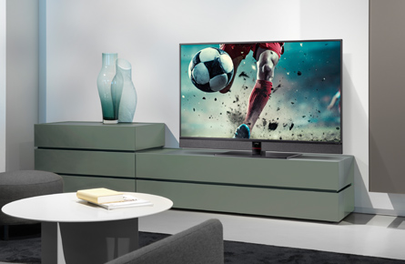 Fernseher mit Fußball und unterer Hälfte eines Fußballspielers in modernem Wohnzimmer