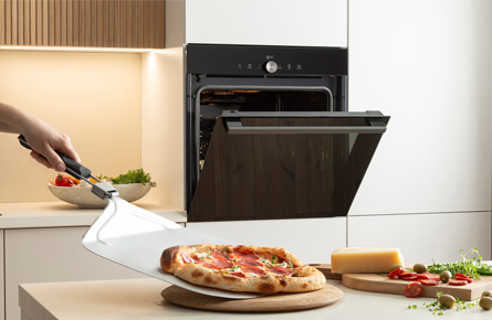 Geöffneter Ofen mit frischer Pizza und einer Abbildung die 77L Ofenvolumen suggeriert
