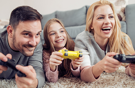 Familie liegt auf einem Teppich und spielt Videospiele