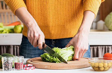 Person schneidet Salat mit einem großen Messer