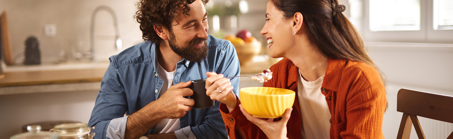 Ein Mann und eine Frau sitzen in der Küche und essen Müsli und trinken Kaffee