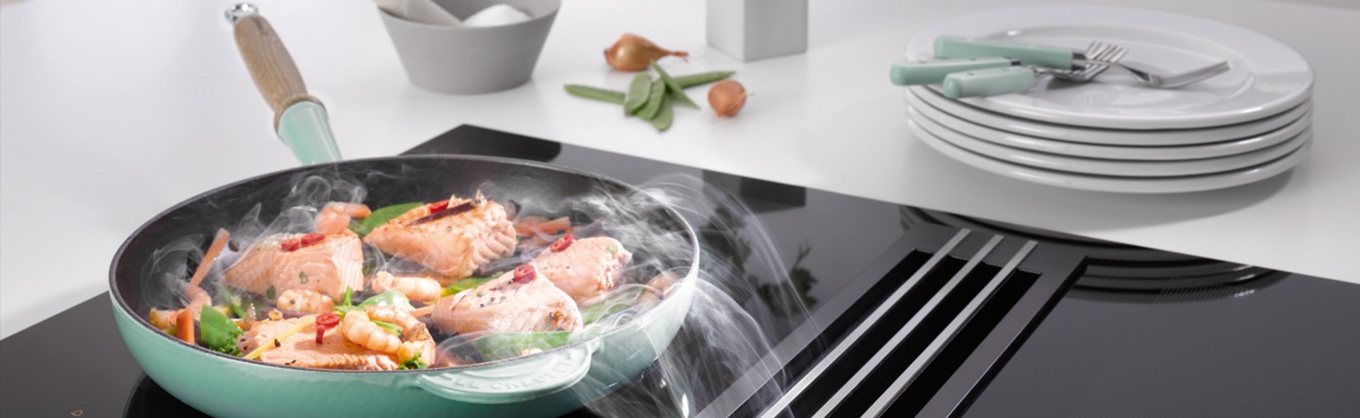 Pfanne mit Essen auf Induktionskochfeld mit Dunstabzugshaube