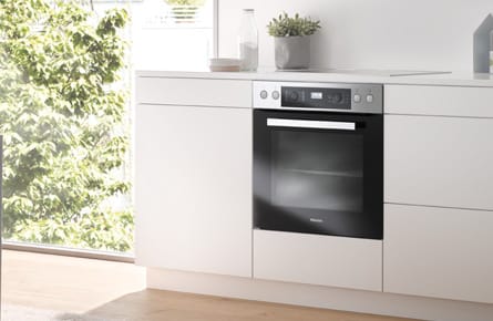 Moderne Küche mit eingebautem Backofen und Kochfeld in einer hellen Küchenzeile