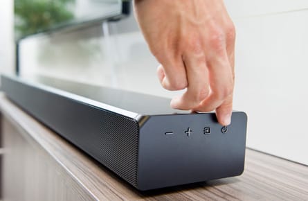 Hand die einen Knopf einer Soundbar betätigt