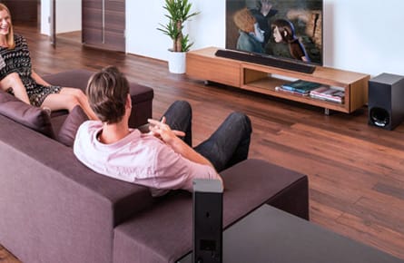 Familie sitzt vor dem Fernseher mit Soundbar