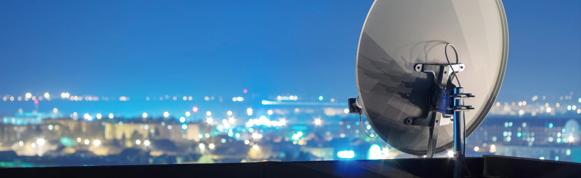 Satellitenschüssel im Vordergrund, Stadt im Hintergrund